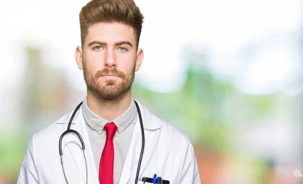 Νέος Ωραίος Γιατρός Άνθρωπος Φορώντας Ιατρική Παλτό Χαλαρή Σοβαρή Έκφραση — Φωτογραφία Αρχείου