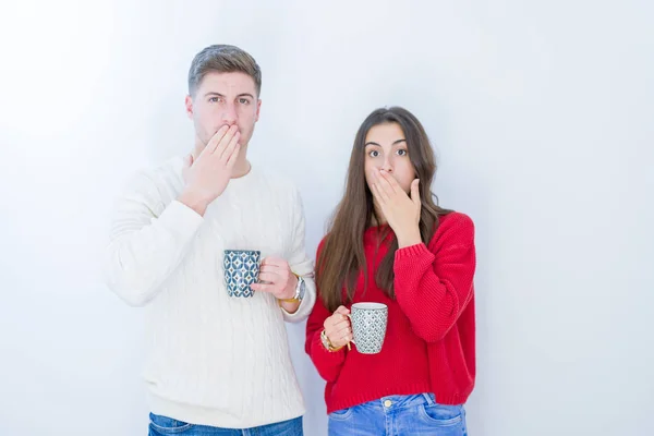美丽的年轻夫妇在白色孤立的背景喝一杯咖啡盖嘴与手震惊与耻辱的错误 表达恐惧 害怕在沉默 秘密的概念 — 图库照片