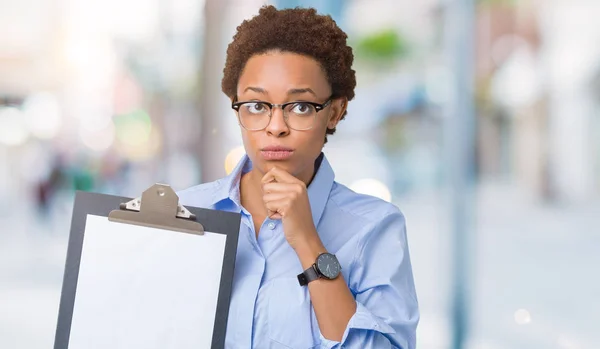 クリップボードに関する質問は 非常に混乱して考え分離背景深刻な顔を考えての上に保持している若いアフリカ系アメリカ人ビジネス女性 — ストック写真