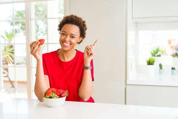 年轻的非洲裔美国妇女吃新鲜的草莓早餐很高兴指着手和手指的一侧 — 图库照片