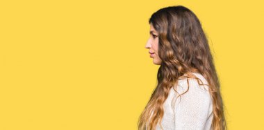 Tarafa bakarak beyaz kazak giyen genç güzel kadın dinlenmek doğal yüz emin gülümseme ile pozuyla profili.