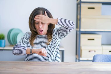 Orta yaş yaşlı kadın evde masada oturan saat zaman endişeli, geç almaktan korkuyor bakıyorum