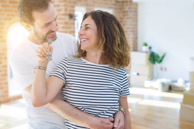 Orta yaş Senior romantik çift Holding ve yeni bir eve taşımak için mutlu gülümseyen ev anahtarlarını gösteren