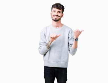 Yakışıklı delikanlı üzerinde sweatshirt giyen izole arka plan emin gülümseyen arkasından el ve kadar başparmak ile işaret