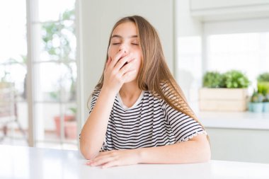 Çizgili t-shirt giyen güzel genç kız çocuk el ile ağız kapsayan yorgun esneme sıkılmış. Huzursuz ve uykululuk.