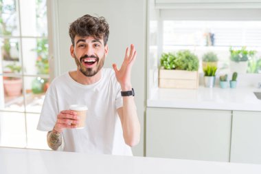 Genç adam sabah çok mutlu ve heyecanlı bir kağıt fincan bir kahve içme, kazanan ifade büyük bir gülümseme ile çığlık zafer kutluyor ve ellerini kaldırdı