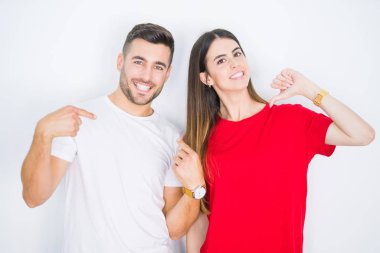 Genç güzel çift birlikte beyaz izole arka plan üzerinde yüzünde gülümseme ile emin görünümlü, parmakları gururlu ve mutlu kendini işaret.