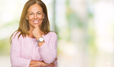 Emin çapraz kollar ve çeneme kaldırdı el ile gülümseme ile kameraya bakarak izole arka plan üzerinde kış kazak giyen güzel orta yaş yetişkin kadın. Pozitif düşünce.