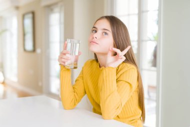 Güzel genç kız çocuk yan el ve parmak ile işaret çok mutlu bir bardak su içme