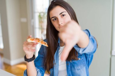 Kızgın yüzile lezzetli pizza bir dilim yemek güzel genç kadın, başparmak aşağı, ret kavramı ile sevmediğimi gösteren negatif işareti