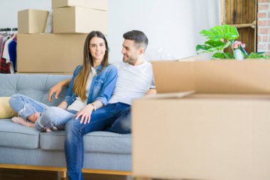 Yeni evde kanepede oturan rahatlatıcı aşk genç çift, yeni daireye taşımak için mutlu gülümseyen