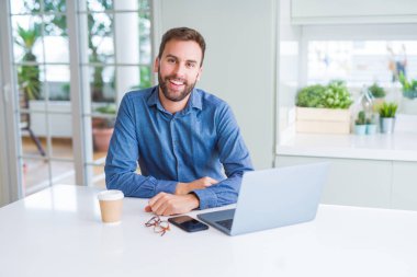 Yakışıklı iş adamı çalışma kullanma bilgisayar dizüstü ve gülümseyen