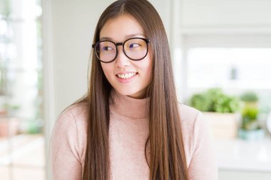 Gözlüklü görünümlü yan ve dik dik bakma uzağa düşünce gülümseyen güzel Asyalı kadın.