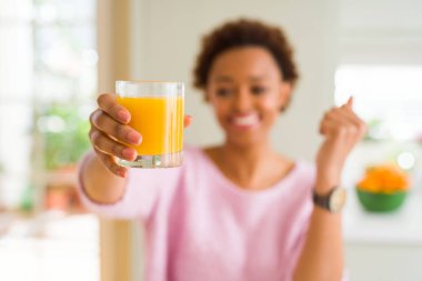 Genç afro-amerikan kadın evde gurur çığlık portakal suyu damlayan ve zafer ve başarı kutluyor çok heyecanlı, duygu tezahürat