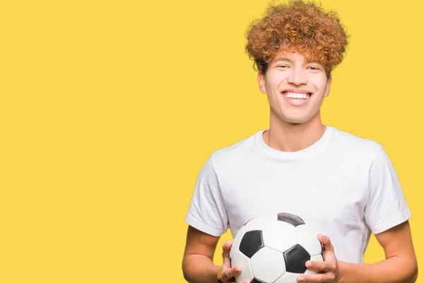 幸せそうな顔をして 歯を見せる自信のある笑顔でサッカーボールを持つ若いハンサムな男 — ストック写真