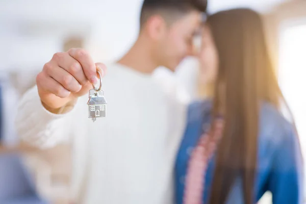 Young asian couple holding keys of new house, smiling happy and excited moving to a new apartment