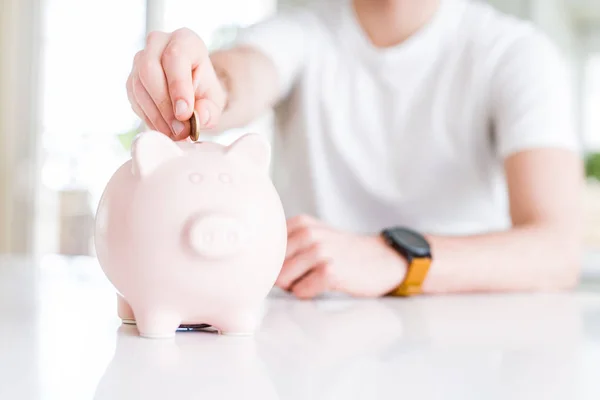 Close up van de man brengen van een munt binnen piggy bank als sparen of in — Stockfoto