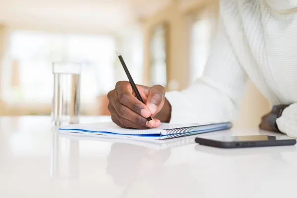 Close-up van de Afrikaanse man het schrijven van een briefje op een papier — Stockfoto