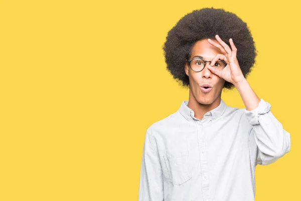 眼鏡をかけたアフロの髪の若いアフリカ系アメリカ人の男性は ジェスチャーをして 驚きの顔 目を指を通して見てショックを受けた くらませ式 — ストック写真