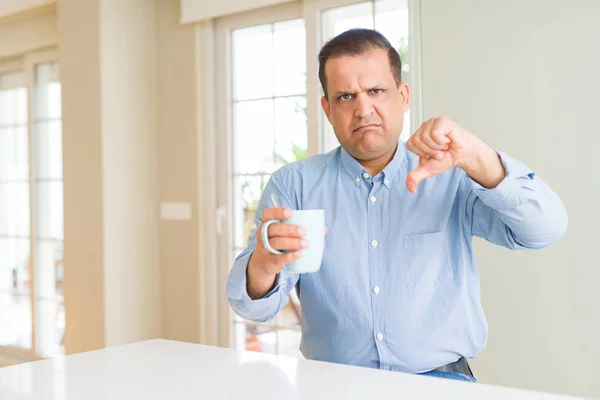 怒った顔で朝にコーヒーを飲む中年男性 親指を下げて嫌いを示すネガティブサイン 拒絶概念 — ストック写真