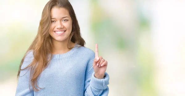 年轻美丽的黑发女人穿着蓝色的冬季毛衣在孤立的背景显示和手指第一指向 同时微笑着自信和快乐 — 图库照片