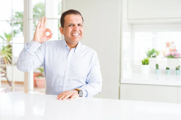 Mężczyzna Średnim Wieku Siedzi Domu Uśmiechnięty Pozytywny Robi Znak Ręki — Zdjęcie stockowe