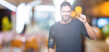 Genç yakışıklı adam üzerinde kazak giyiyor izole arka plan gülümseyen ve emin işaret ile el yapıyor boyutu işareti yaparken parmaklar ve kamera bakıyor. Ölçü kavramı.