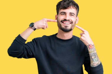 Tecrit edilmiş, güler yüzlü, kendine güvenen, parmaklarını, dişlerini ve ağzını gösteren genç yakışıklı bir adam. Sağlık kavramı.