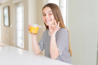 Güzel genç kız çocuk parmakları ile ok işareti yapıyor taze portakal suyu bir bardak içme, mükemmel sembol