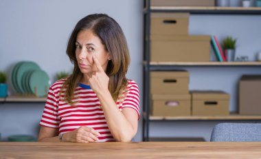 Evde masada oturan orta yaş yaşlı kadın seni izleyen göz işaret, şüpheli ifade