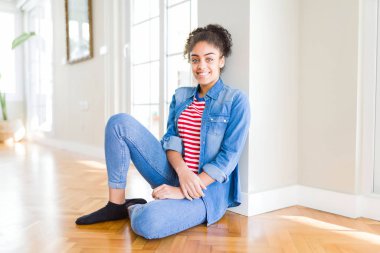 Yüzünde mutlu ve güzel bir gülümseme ile katta oturan afro saçlı güzel genç Afro-Amerikan kadın. Şanslı kişi.