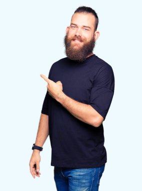 Yüze mutlu ve doğal ifade ile yan kadar el ve parmak ile işaret yüz bir gülümseme ile neşeli rahat t-shirt giyen genç sarışın adam