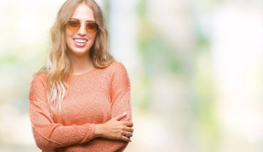 Güzel genç sarışın kadın üzerinde güneş gözlüğü takıyor mutlu yüz ile gülümseyerek kameraya seyir silah geçti arka plan izole. Olumlu bir kişi.