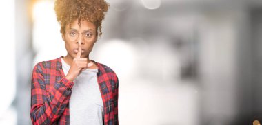 Dudaklarında parmak ile sessiz olmanı izole arka plan üzerinde gözlük güzel genç Afro-Amerikan kadın. Sessizlik ve gizli kavramı.