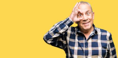 Yakışıklı komuta sizde rahat gömlek gülümseyen, parmakları ile mutlu yüz üzerinden seyir göz el ile ok jest yapıyor.