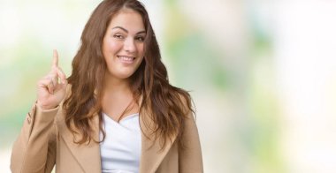 Artı boyutu genç kadın güzel üzerinde kış palto giyiyor arka plan işaret parmağı kadar başarılı fikirle izole. Çıktıktan ve mutlu. Bir numara.