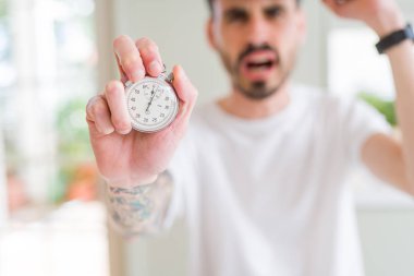 Stopwatch tutan genç adam kızgın ve sinirli öfke, deli ve yükseltilmiş el, öfke kavramı ile bağırarak sinirli