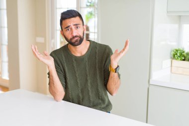 Yakışıklı İspanyol giyen sıradan kazak ev clueless ve şaşkın bir ifadeyle kollar ve eller kaldırdı, dostum. Şüphe kavramı.