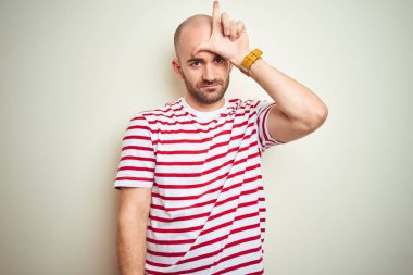 Sakallı genç kel adam beyaz izole arka plan üzerinde rahat çizgili kırmızı t-shirt giyen alnına parmakları ile insanların alay ve hakaret yapma.