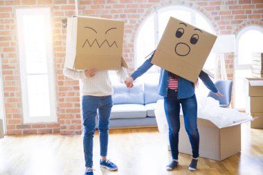 Çılgın çift kafa üzerinde komik yüzler ile kutuları giyiyor, yeni bir eve taşımak için mutlu eğlenceli