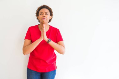 Beyaz arka plan üzerinde genç güzel afro-amerikan kadın dilencilik ve elleri ile birlikte umut ifade ile dua yüzünde çok duygusal ve endişeli. Af dilemek istiyorum. Din kavramı.