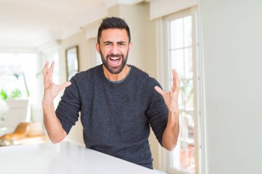 Casual kazak evde çılgın ve kızgın bağırarak ve agresif ifade ve silah kaldırdı bağırmaya giyen yakışıklı İspanyol adam. Hayal kırıklığı kavramı.