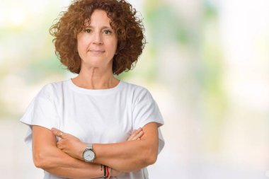 Üzerinde beyaz t-shirt giyen güzel orta ager üst düzey kadın arka plan gevşek yüzünde ciddi bir ifade ile izole. Basit ve çapraz silah ile doğal
