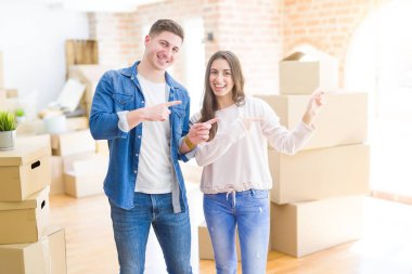 Güzel genç çift gülümseyerek yeni bir eve hareket ve yan iki el ve parmakları ile işaret kamera bakıyor.