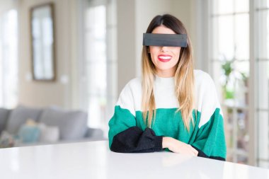 Genç güzel kadın gözleri siyah sansür bant ile evde mutlu ve serin bir gülümseme ile yüzünde. Şanslı kişi.