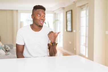Afro-Amerikan yakışıklı beyaz tablo evde seyir ve başparmak yanında yukarıyı mutlu yüz ile gülümseyen.