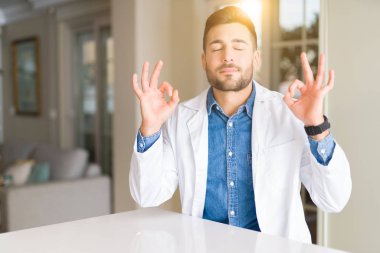 Genç yakışıklı Doktor adam klinikte rahatla ve gülümseyen gözlerle parmak ile meditasyon jest yapıyor kapalı. Yoga kavramı.
