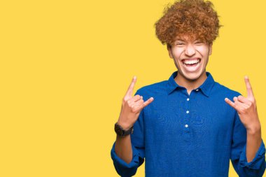 Afro saçlı genç yakışıklı zarif adam elleri yukarı ile rock sembolü yapıyor deli ifade ile bağırıyor. Müzik yıldızı. Ağır konsept.