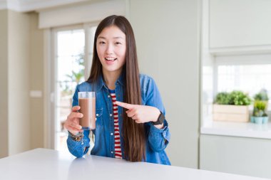 Güzel Asyalı kadın el ve parmak ile işaret çikolata milkshake çok mutlu bir bardak içme