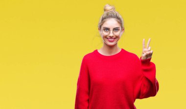 Gösterilen ve parmakları ile işaret izole arka plan üzerinde kırmızı kazak ve gözlük giyen genç güzel sarışın kadın ikincisi ise kendinden emin ve mutlu gülümseyerek.